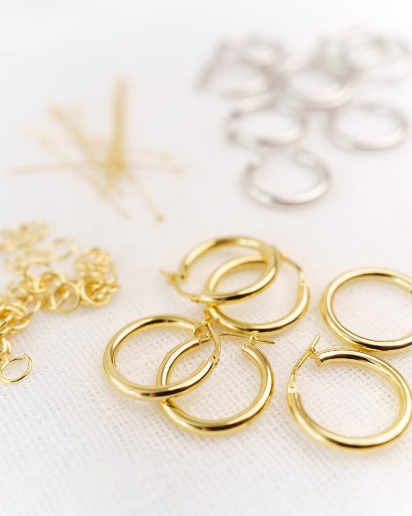 Kuvassa näkyy hopeisia ja kultaisia korvakorujen osia vaalealla taustalla