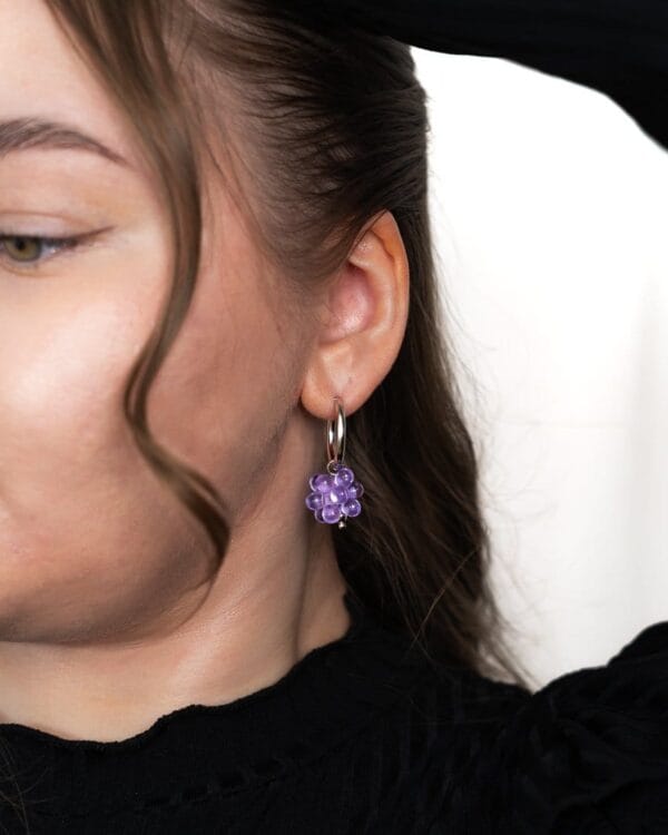 Sovituskuva hopeisista korvakoruista liiloilla helmillä