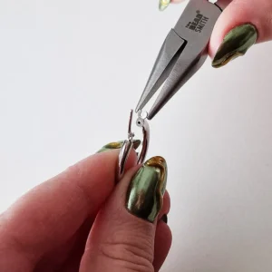 Kuvassa kiristetään korvakorurenkaan lukkoa