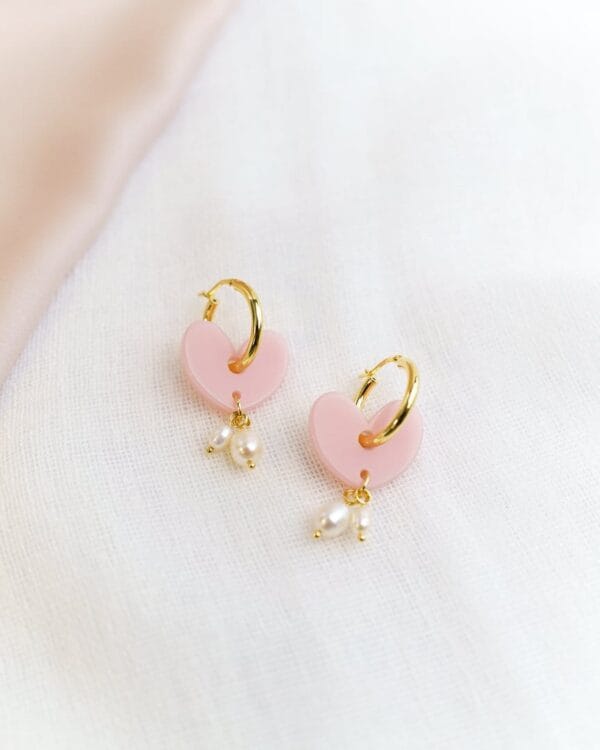 Sydämen muotoiset valeanpunaiset korvakorut helmillä ja kultaisilla korvakorurenkailla