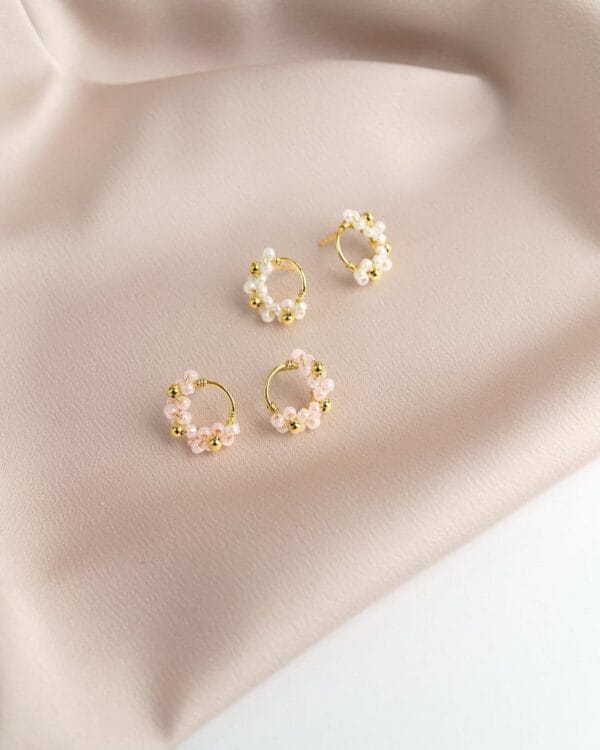 Kahdet pienet kultaiset nappikorvakorut pienillä helmillä