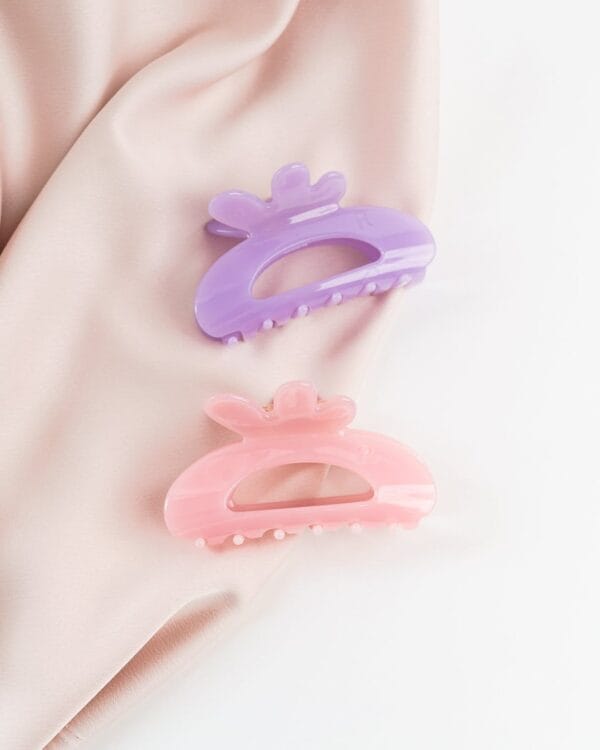 Kaksi eriväristä isoa hiusklipsiä vaalealla taustalla