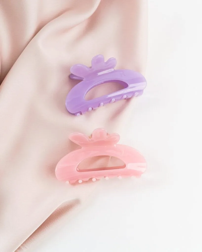 Kaksi eriväristä isoa hiusklipsiä vaalealla taustalla