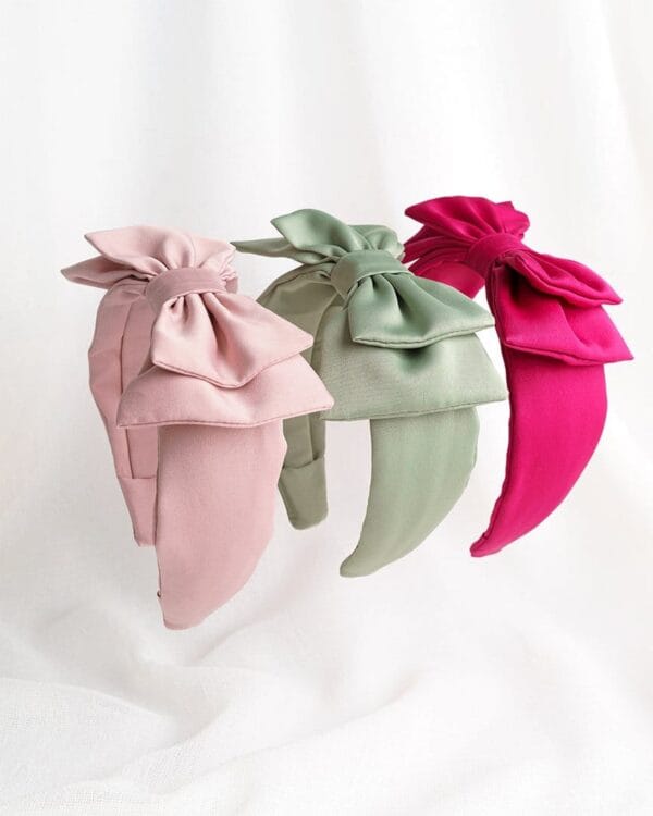 Kolme satiinista rusettihiuspantaa vierekkäin