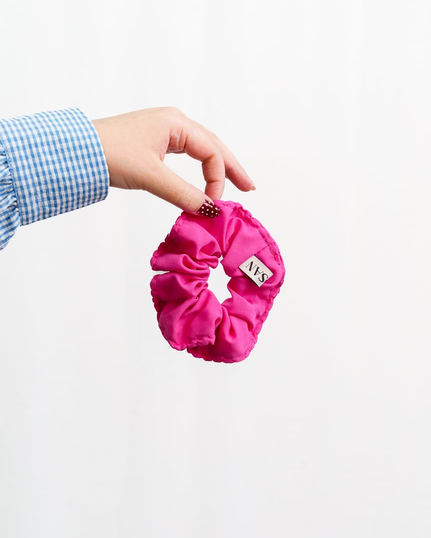 Kuvassa vaaleaa taustaa vasten ksäi joka roikottaa pinkkiä hiusdonitsia.