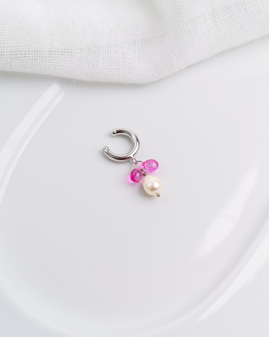 Kuvassa vaalealla taustalla valkoinen astia, jonka päälle aseteltu earcuff korvakoru.